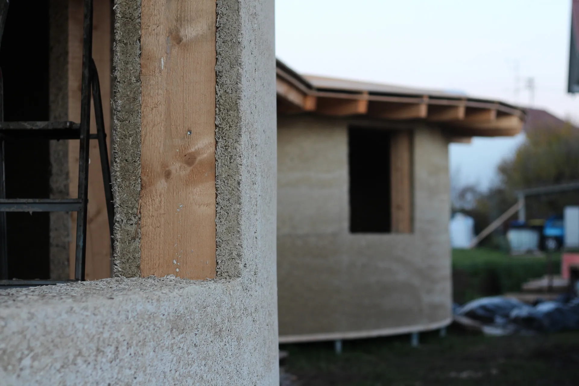 Hanfkalk-Wand im Detail vor einem Rundbau aus Naturbaustoffen