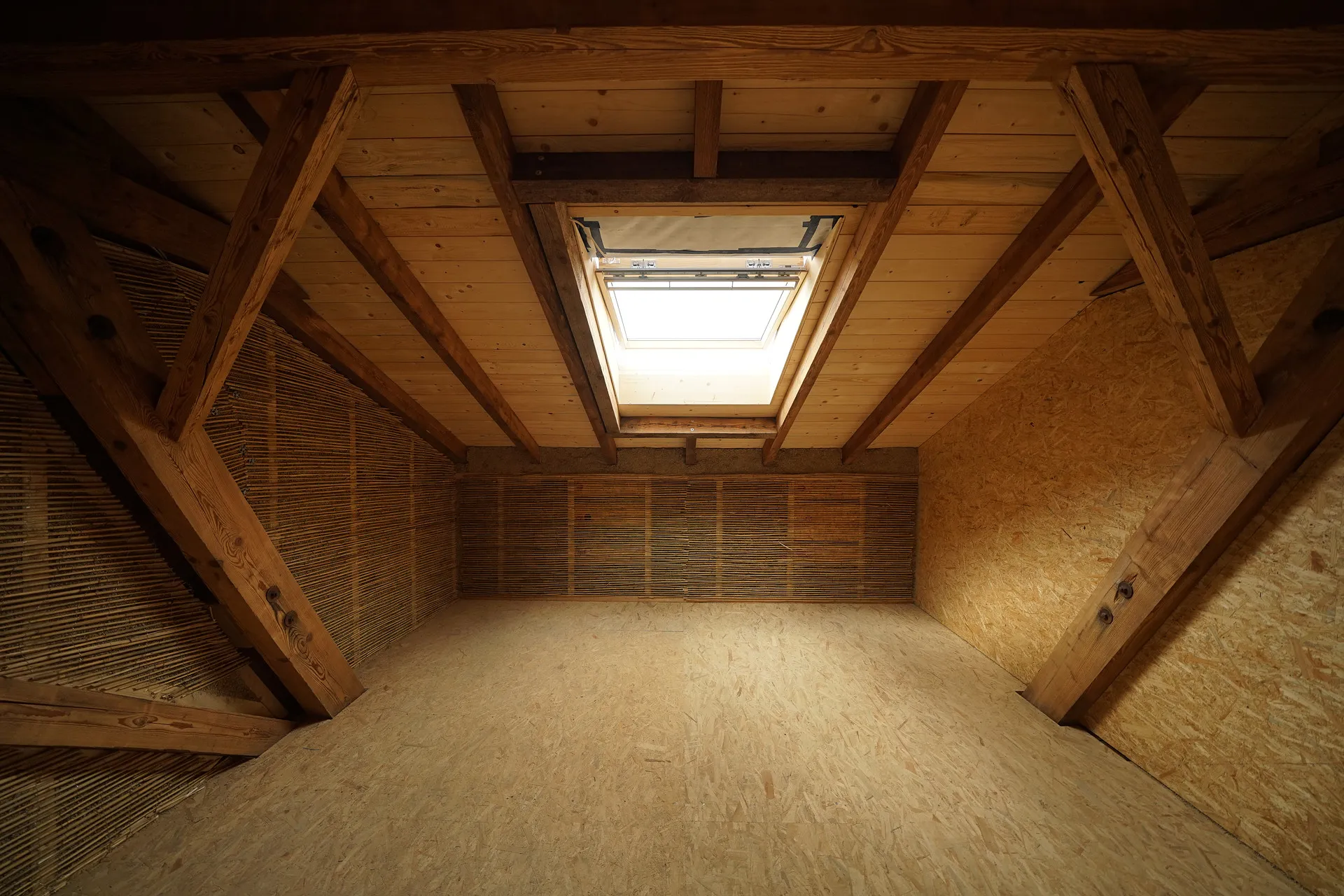 An attic space finished with natural materials: timber beams, reed insulation and a skylight